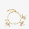 Bracciale con nastri e ciondoli multipli Bracciale in metallo dorato con ciondoli, nastri e perle Bracciale con nastri e ciondoli multipli Bracciale in metallo dorato con ciondoli, nastri e perle