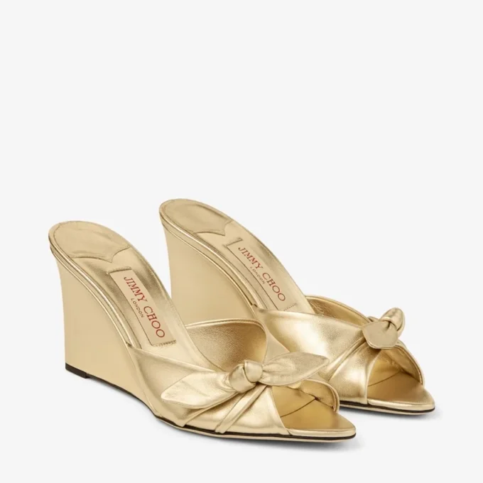 Livi Wedge 85 Mules con zeppa in nappa metallizzata dorata con fiocco Livi Wedge 85 Mules con zeppa in nappa metallizzata dorata con fiocco