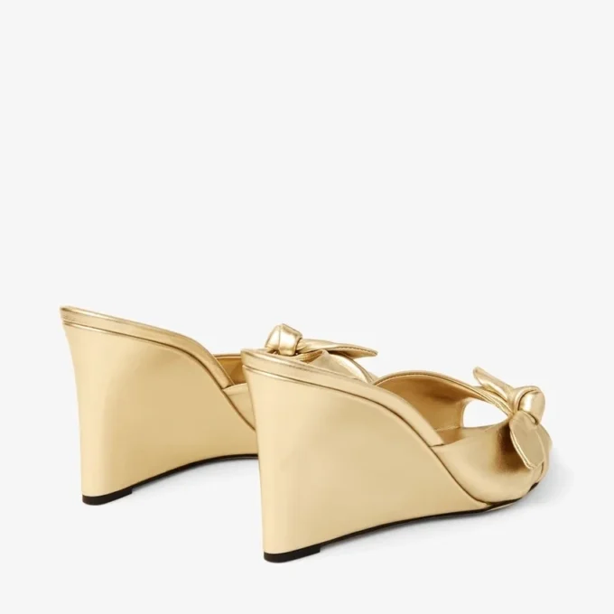 Livi Wedge 85 Mules con zeppa in nappa metallizzata dorata con fiocco Livi Wedge 85 Mules con zeppa in nappa metallizzata dorata con fiocco
